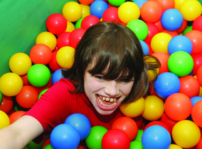 Young man with a disability playing in a ball pool.